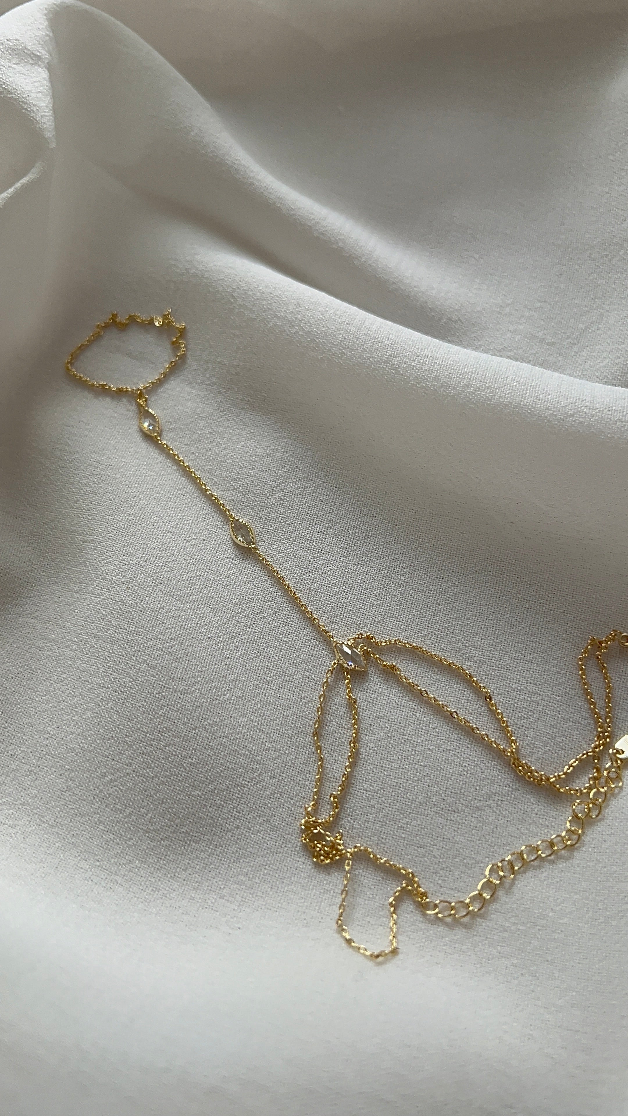 Goldfarbene Handkette mit feiner Gliederkette und Ringdetail